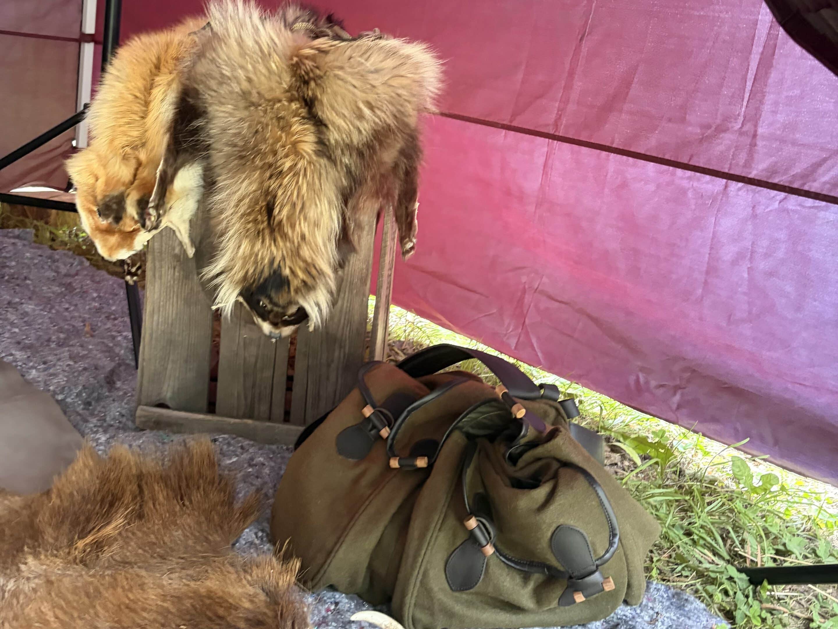 Marderhund, Fuchs und ein Jagdrucksack liegen auf bzw. neben einer Holzkiste